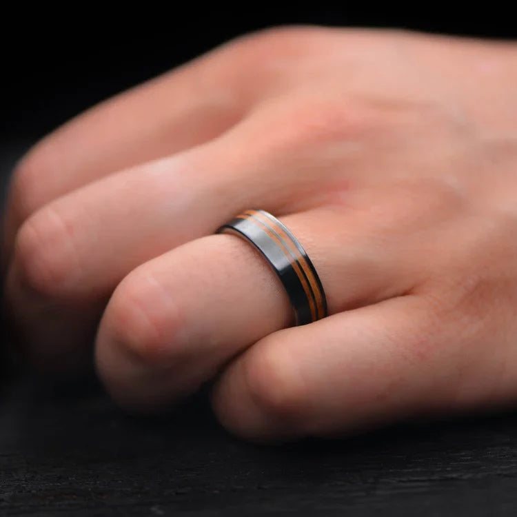 Black titanium wedding band with Western maple burl inlays on a hand, featuring a unique brushed finish, 7mm mens ring, free engraving available.
