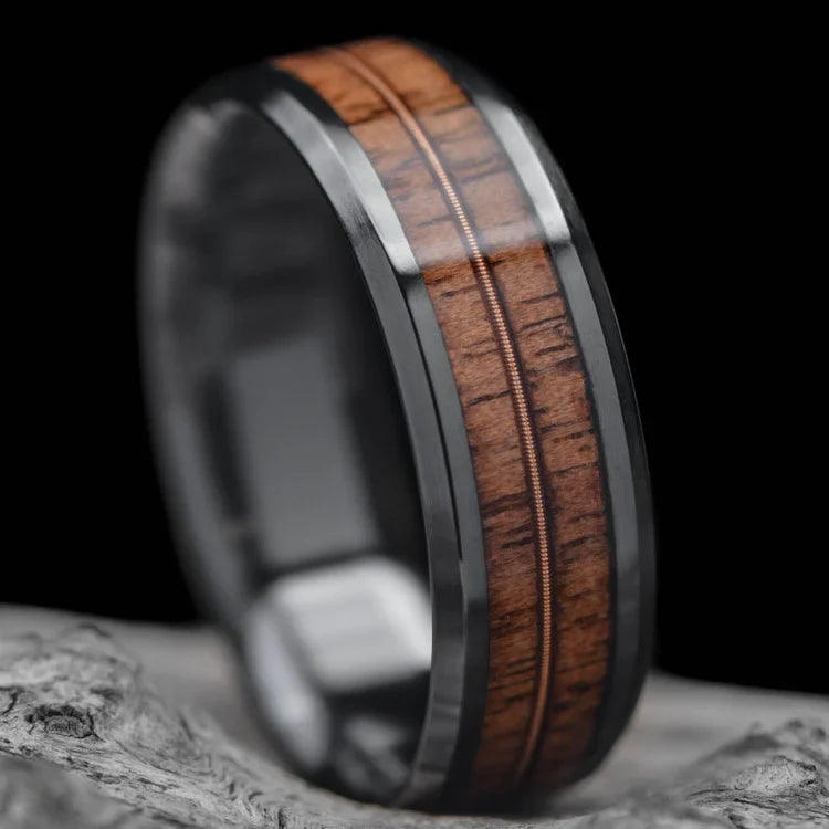 Black titanium wedding band with dual walnut and guitar string inlays, free engraving, 8mm mens ring, polished bevel profile, displayed on a white sea branch.