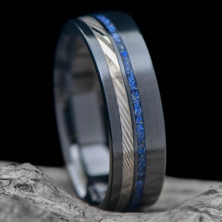 Black titanium wedding band with dense twist and lapis lazuli inlays, 7mm mens ring, unique design, free engraving, displayed on white sea branch.