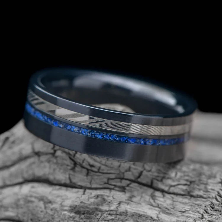 Black titanium wedding band with dense twist design and lapis lazuli inlays, 7mm mens ring, unique style, free engraving, displayed on a white sea branch.