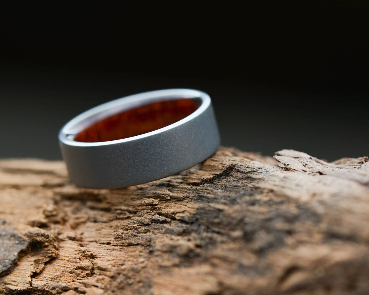 Sand Blasted Titanium ring with wood inner band on old wood