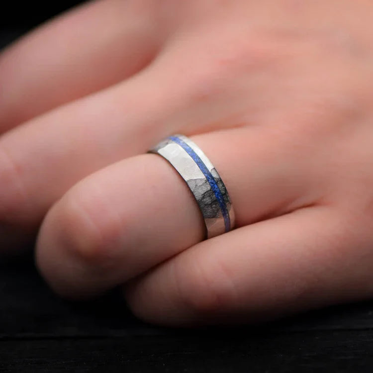 Faceted titanium wedding band with lapis lazuli inlay on a hand, featuring free engraving, 7mm mens domed ring, unique custom mens wedding band.