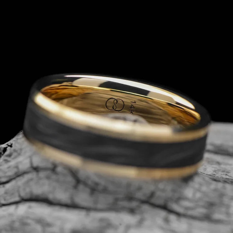 14K yellow gold mens wedding band with central forged inlay, 7mm width, polished bevel profile, custom engraving available, displayed on a white sea branch.