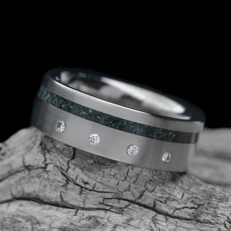 Titanium wedding band with moss agate inlay and flush set diamond, 7mm mens ring, brushed flat profile, displayed on white sea branch, free engraving available.