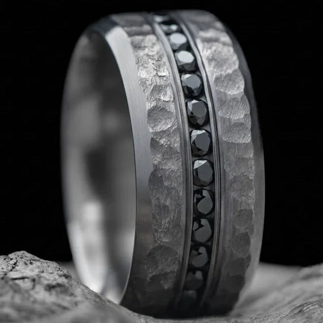 Tantalum wedding band with eternity set precious stones, mens 10mm faceted bevel profile ring, free engraving, displayed on a white sea branch.