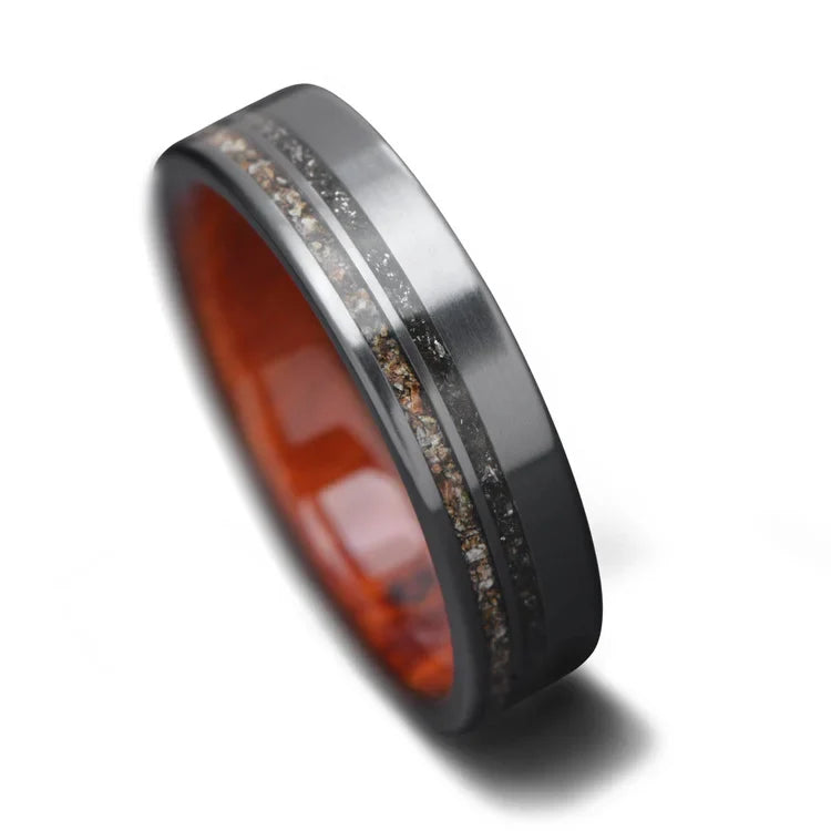 Black titanium wedding band featuring meteorite and crushed T-Rex inlays, mens matte flat profile ring, 6mm, unique mens ring, free engraving available, displayed on a white background.