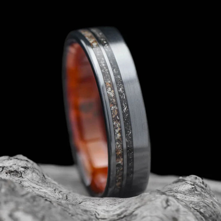 Black titanium wedding band with meteorite and crushed T-Rex inlays, 6mm mens matte flat profile ring, unique mens ring, free engraving, displayed on a white sea branch.