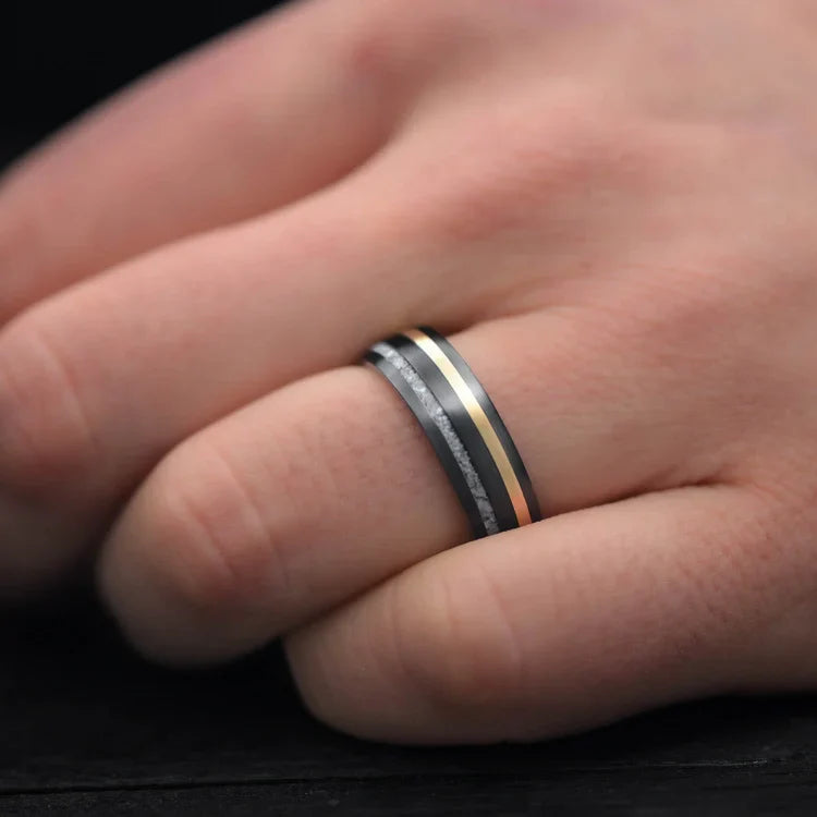 Mens black titanium wedding band with pearl and 18K yellow gold inlays, featuring a brushed domed profile, worn on a hand, unique 7mm mens ring with free engraving option.