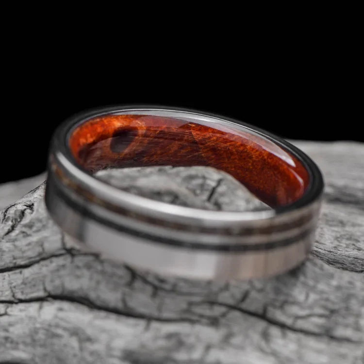 Titanium wedding band with crushed T-Rex and Western Maple Burl inlays, 6mm mens ring, unique custom design, free engraving, displayed on a white sea branch.
