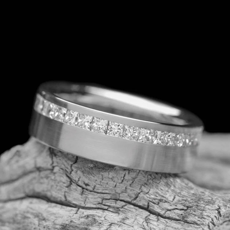 10KW brushed flat band mens wedding ring with half eternity princess cut stones, 7mm, custom design, free engraving, displayed on a white sea branch.