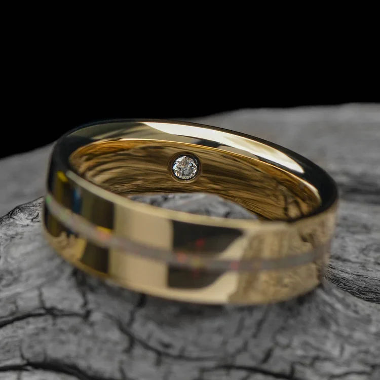 14K yellow gold mens wedding band with central pearl opal inlay and flush set diamond, polished flat profile, 6mm width, displayed on a white sea branch, free engraving available.