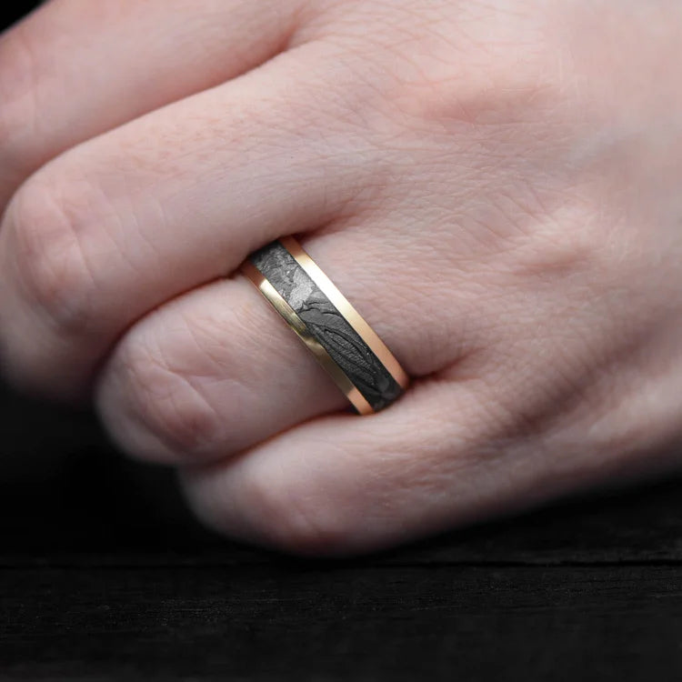 10KY gold wedding band with central meteorite inlay and bloodwood inner sleeve, 7mm mens ring, unique design, free engraving, displayed on white sea branch.