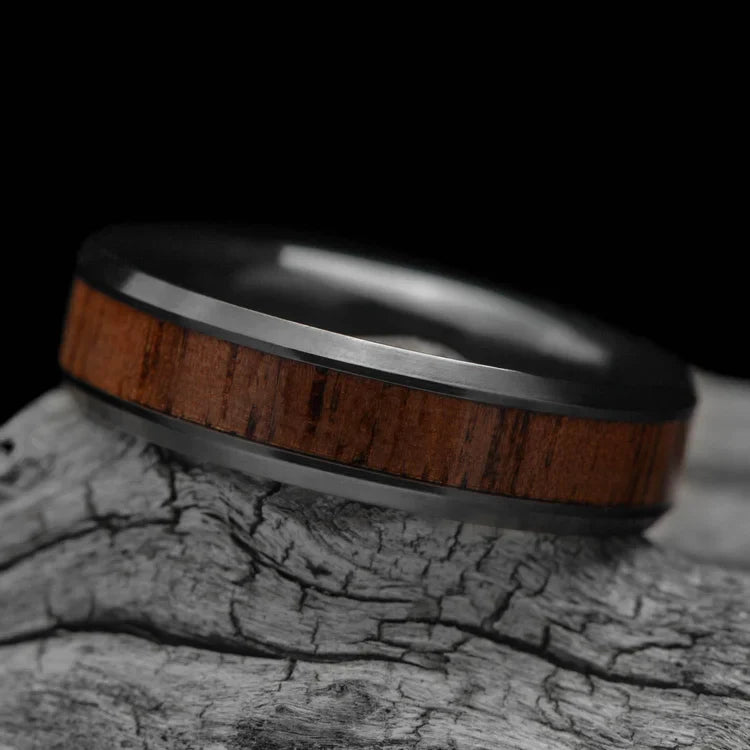 Black titanium wedding band with central walnut inlay, featuring a brushed bevel profile, 6mm mens ring, displayed on a white sea branch, free engraving available.