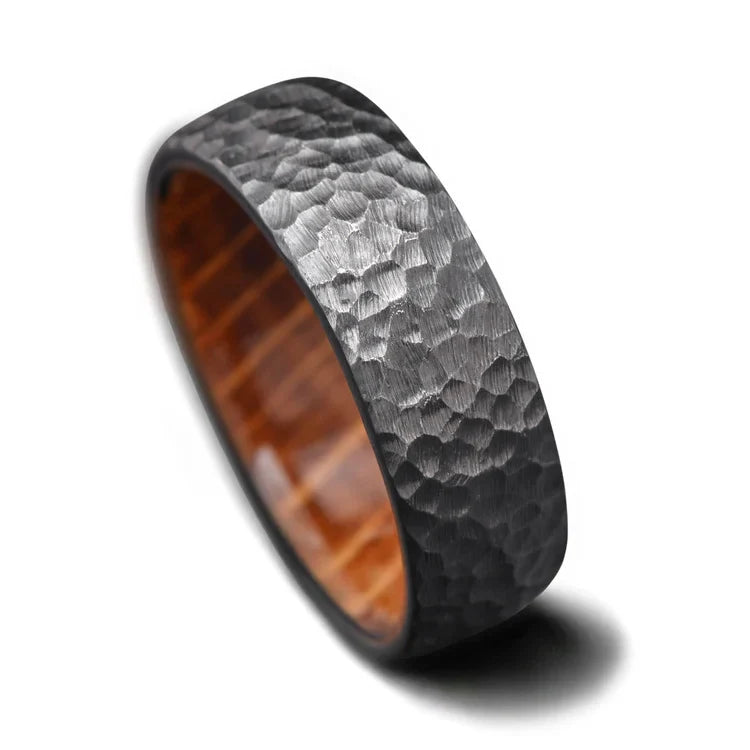 Black titanium wedding band with a whiskey barrel oak inner sleeve, featuring a hammered domed design, 7mm width, for men, showcasing unique craftsmanship and free engraving options on a white background.
