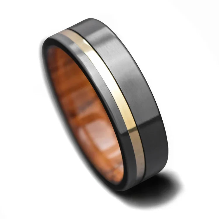 Mens 7mm black titanium wedding band with 18K yellow gold inlay and olivewood inner sleeve, brushed flat profile, free engraving option, on a white background.