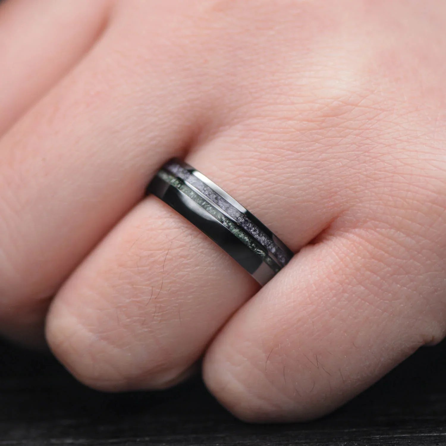 Hand wearing a Black Titanium Wedding Band featuring Amethyst and Moss Agate inlays, showcasing a 6mm domed polished design, perfect for a unique mens wedding band with free engraving.