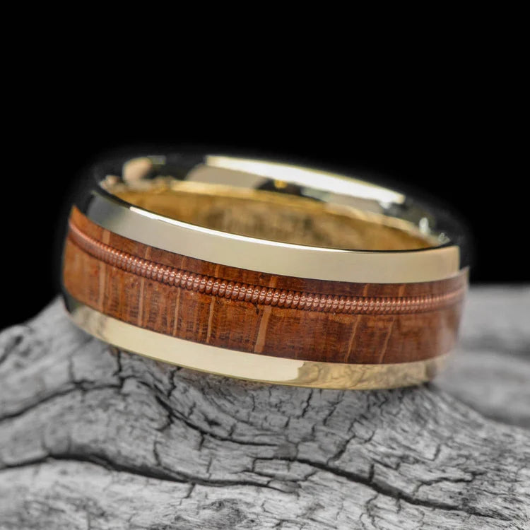 10KY gold wedding band with guitar string and whiskey barrel oak inlay, 8mm mens ring, unique design, free engraving, displayed on a white sea branch.