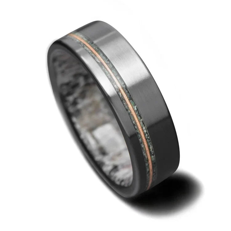 Black titanium wedding band featuring moss agate and guitar string inlays, 7mm mens ring with deer antler inner sleeve, free engraving available, displayed on a white background.