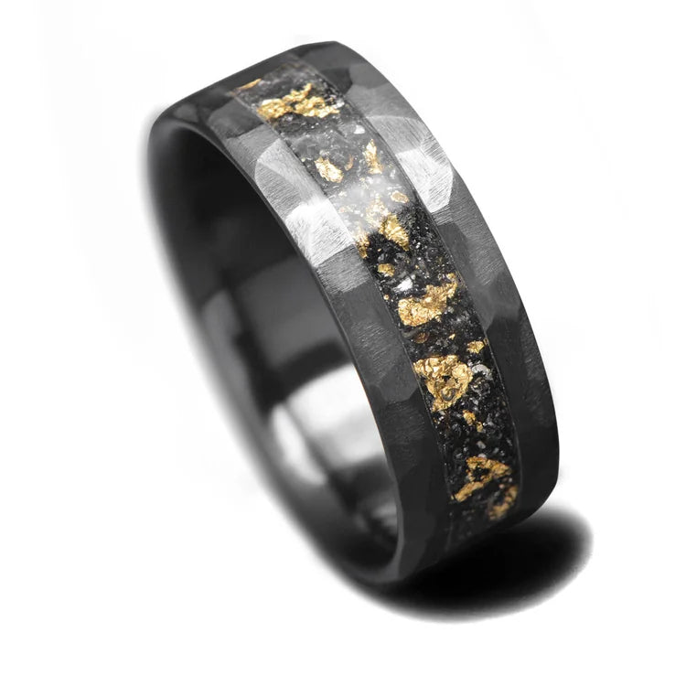 Black titanium mens wedding ring featuring a central meteorite and gold leaf inlay, 8mm wide, offering free engraving, displayed on a white background.