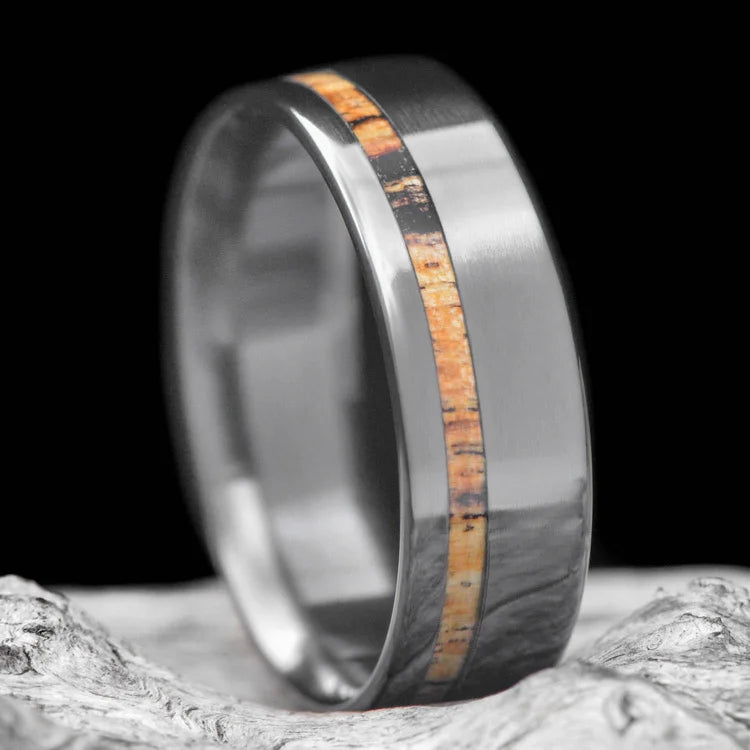 Black Titanium Wedding Band with Silver Spalted Birch Inlay, 7mm Mens Wedding Ring, Customizable with Free Engraving, displayed on a white sea branch.