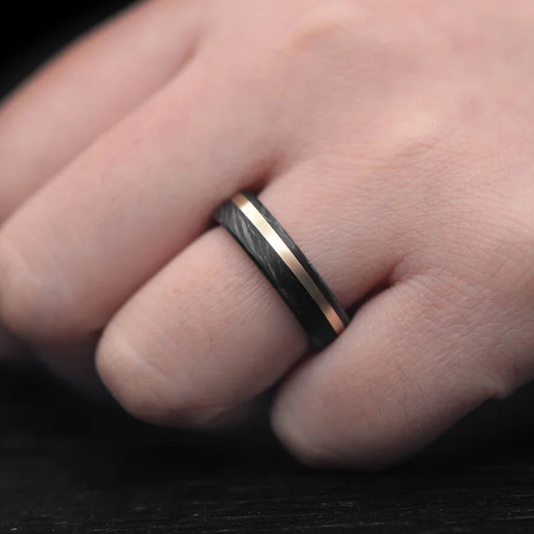 Mens 6mm forged wedding band with 14K yellow gold and black fire opal inlay, brushed flat profile, free engraving, shown on hand.