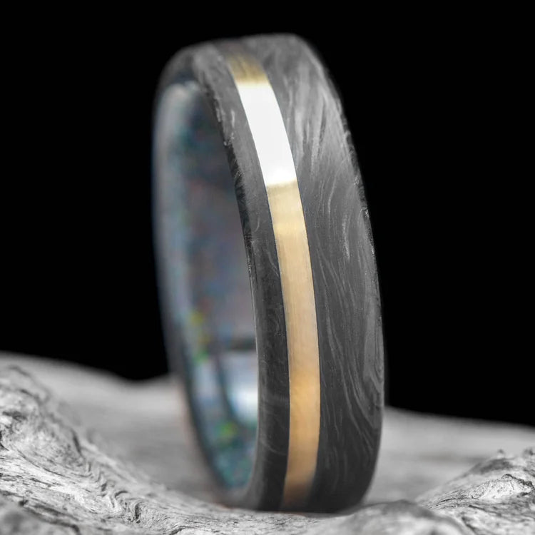 Forged mens wedding band with 14K yellow gold and black fire opal inlay, 6mm brushed flat profile, on white sea branch background, free engraving option available.