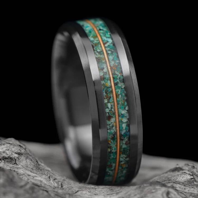 Black titanium wedding band with dual turquoise and central guitar string inlay, 7mm mens ring, unique design, free engraving, displayed on a white sea branch.