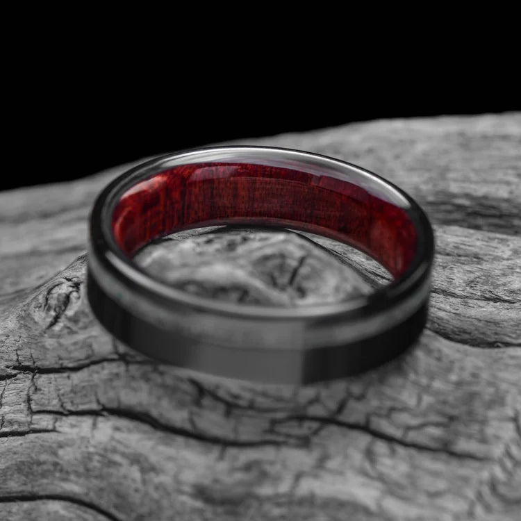 Black titanium mens wedding band with pearl opal inlay and bloodwood inner sleeve, polished flat profile, 6mm, displayed on a white sea branch, free engraving available.