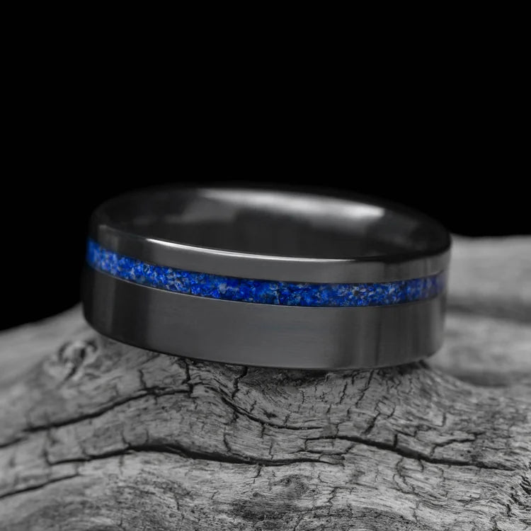 Black titanium ring with lapis lazuli inlay, 8mm mens wedding band with brushed flat profile, unique design, free engraving, displayed on white sea branch.