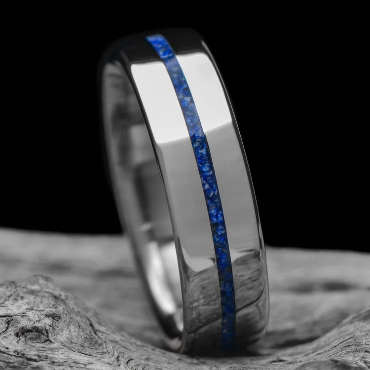 Titanium wedding band with central lapis lazuli inlay, free engraving, 6mm mens ring, polished flat profile, unique design, on white sea branch background.