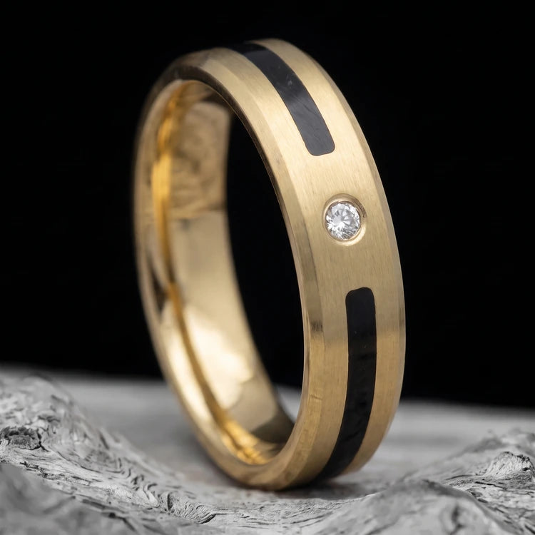 10K yellow gold men’s beveled wedding band with a unidirectional center inlay and brushed finish, resting on a white sea branch.