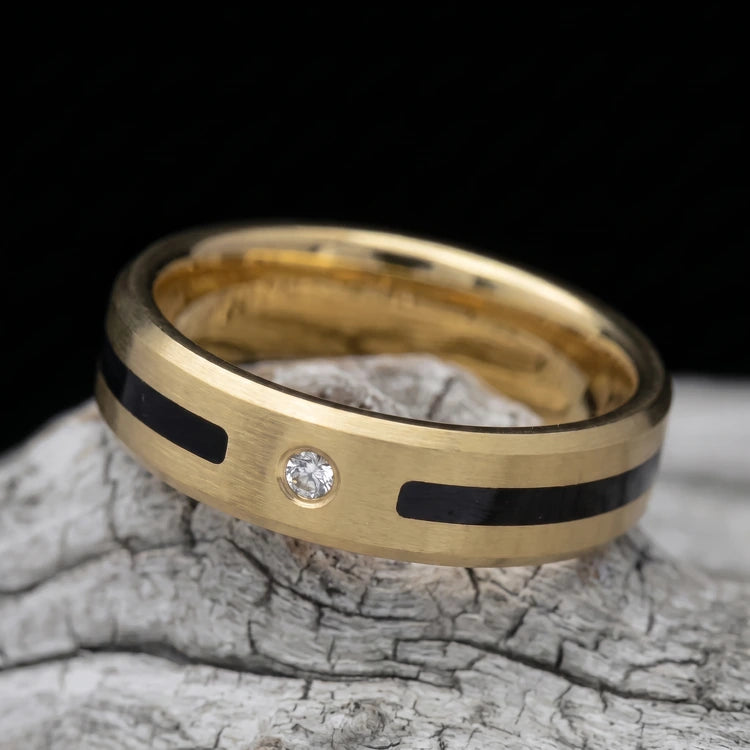 10K yellow gold men’s wedding band with a unidirectional center inlay, brushed finish, and beveled edges, resting on a white sea branch.