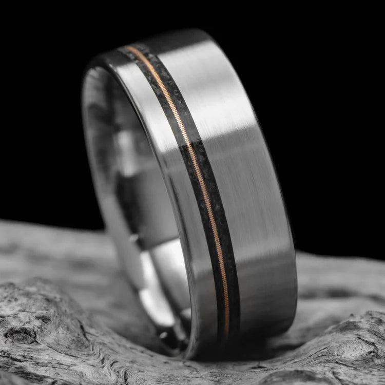 Titanium wedding band with black onyx and guitar string inlay, 8mm mens ring, brushed flat profile, unique design, free engraving, displayed on white sea branch.