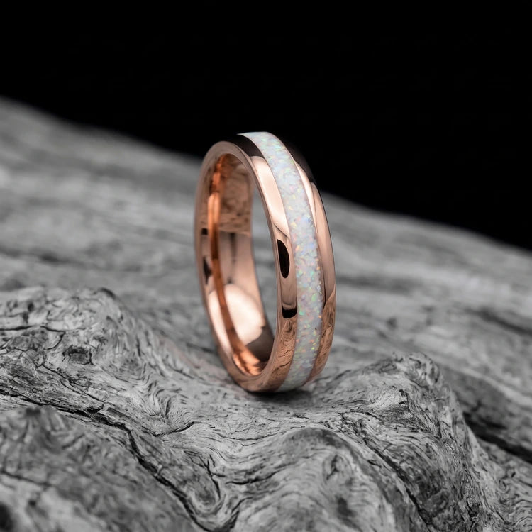10K rose gold men’s wedding band with a central pearl opal inlay, polished domed finish, and 6mm width, resting on a white sea branch.
