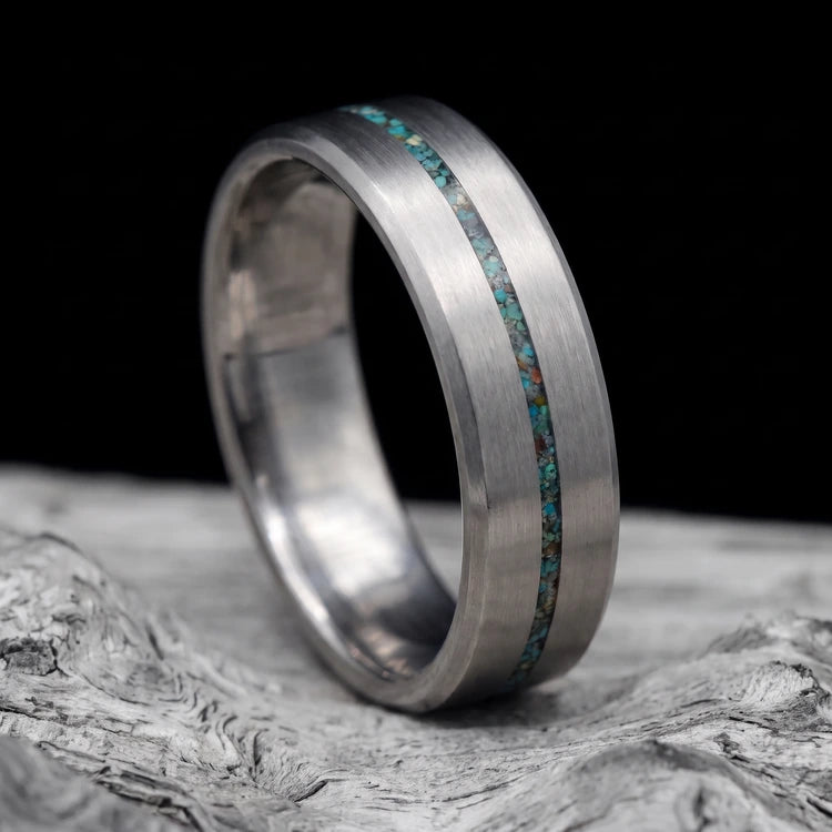 Men’s 8mm brushed tantalum wedding band with a central turquoise inlay and beveled edges, resting on a white seashell.