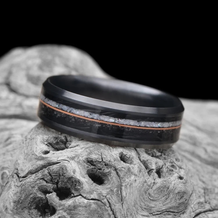 Black Titanium Wedding Band with Pearl & Black Onyx Inlays, 7mm Men's Wedding Ring with Beveled Profile and Polished Finish, laying on white sea branch, free engraving available