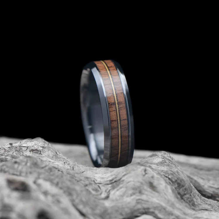 Black Titanium Ring with Walnut and Guitar String Inlays, 6mm Men's Wedding Band, Polished Beveled Profile, Custom Engraving, Laying on White Sea Branch