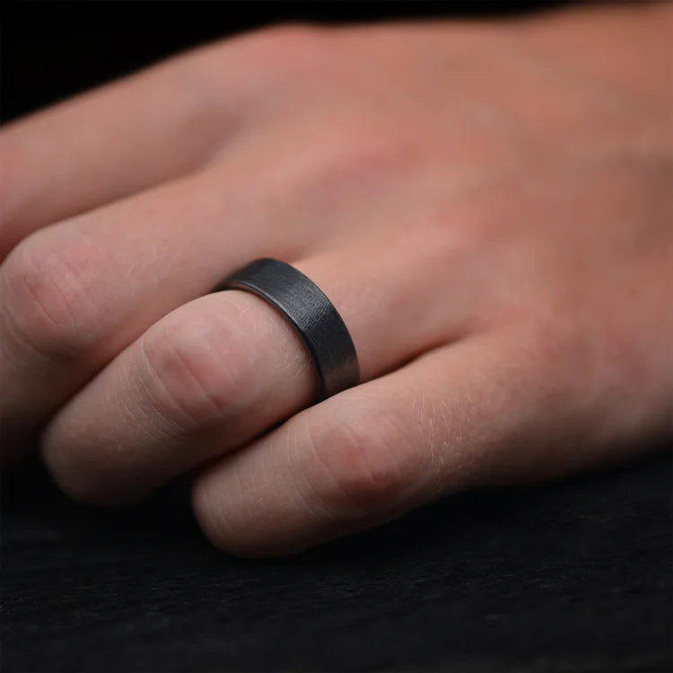 Hand wearing a Black Titanium Wedding Band with Silver Spalted Birch Inner Sleeve, featuring free engraving, 7mm width, unique men's wedding ring.