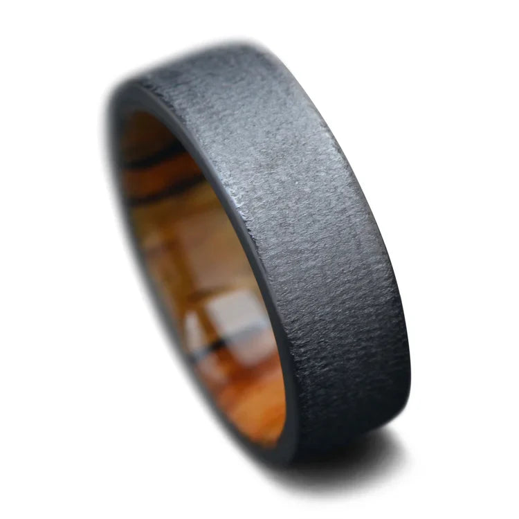 Black titanium wedding band with silver spalted birch inner sleeve, 7mm men's ring, unique design, free engraving option, displayed on a white background.