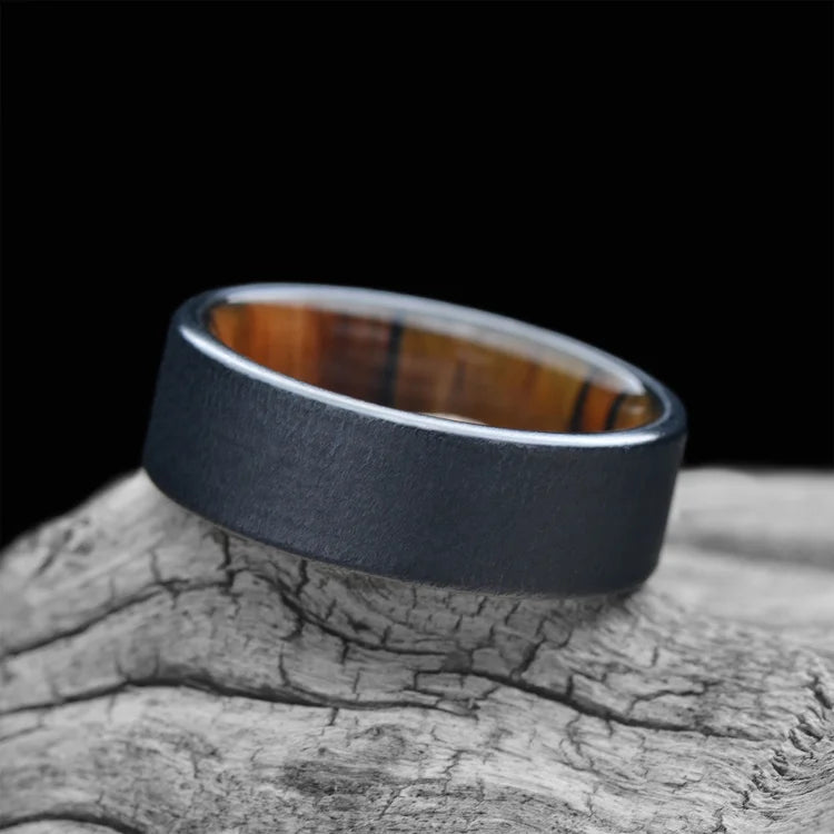 Black titanium wedding band with silver spalted birch inner sleeve, 7mm men's wedding ring, unique men's band, free engraving, displayed on white sea branch.