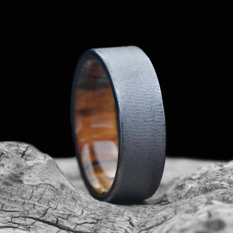 Black Titanium Wedding Band with Silver Spalted Birch Inner Sleeve, 7mm Men's Wedding Ring, Unique Design, Free Engraving, displayed on white sea branch background.