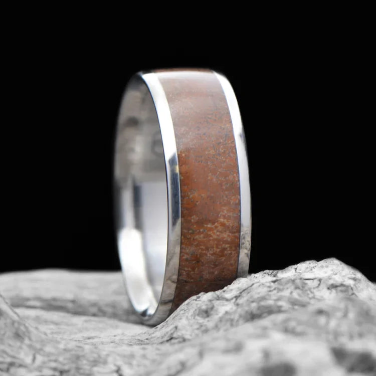 Titanium men's wedding band with central dinobone inlay, 7mm, unique custom design, free engraving, displayed on a white sea branch.