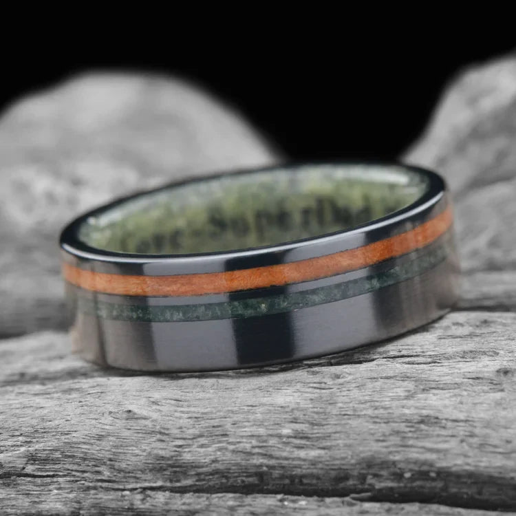 Black titanium wedding band with Western maple burl and moss agate inlays, featuring a jade inner sleeve, 7mm men's unique wedding ring, displayed on a white sea branch, free engraving available.