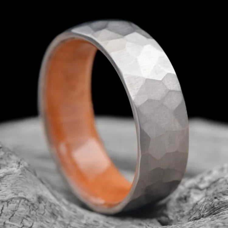 Faceted Titanium Ring with Birds Eye Maple Inner Sleeve, 7mm Mens Wedding Band, Unique Design, Free Engraving, displayed on white sea branch.