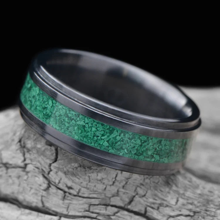 Black Titanium Wedding Band with Central Malachite Inlay, 7mm Mens Wedding Ring, Unique Design, Free Engraving, Laying on White Sea Branch, Elegant and Modern Mens Ring.