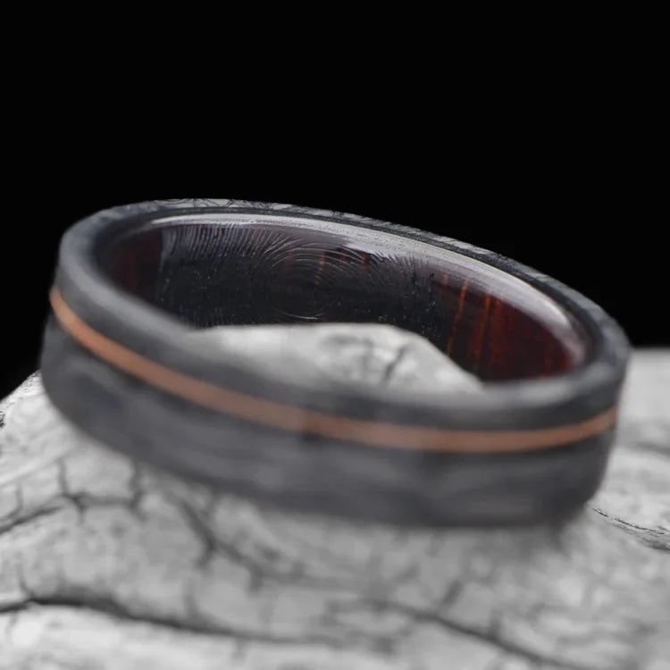 Mens 6mm forged wedding band with meteorite and guitar string inlay, featuring a koa wood inner sleeve and matte finish, displayed on a white sea branch.