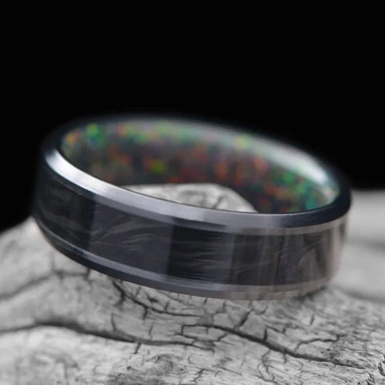 Black titanium wedding band with central forged inlay and black fire opal inner sleeve, 7mm mens ring, polished finish, displayed on a white sea branch, free engraving available.