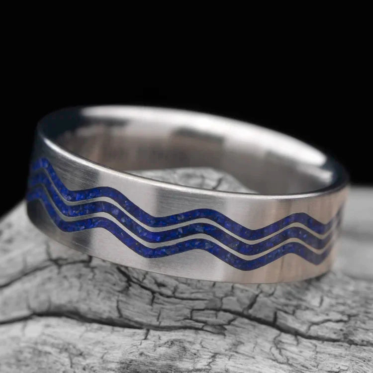Titanium wedding band with lapis lazuli inlay, 7mm mens ring, unique custom design, free engraving, displayed on a white sea branch.
