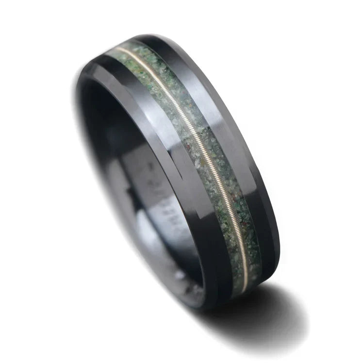 Black titanium wedding band featuring moss agate and guitar string inlays, 7mm mens ring with unique custom design, free engraving available, displayed on a white background.