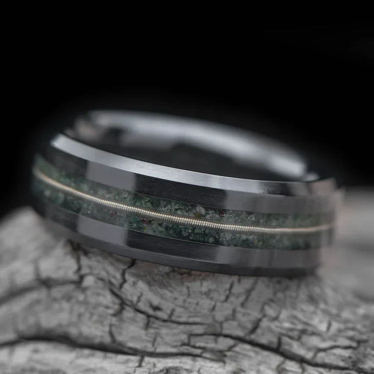 Black titanium wedding band with moss agate and guitar string inlays, 7mm mens ring, unique custom design, free engraving, displayed on a white sea branch.